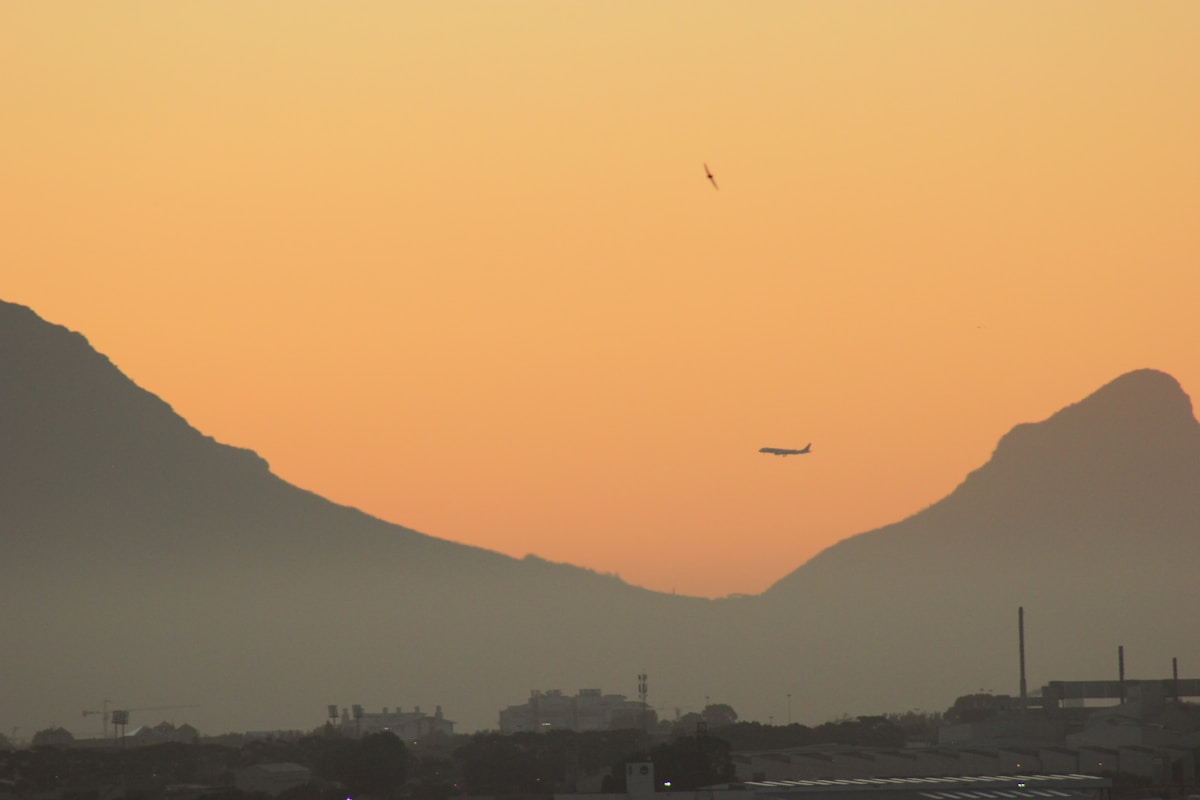 Plane flying over Cape Town with mountain silhouettes at sunset, South Africa — Airlink Cape Town to Zanzibar route