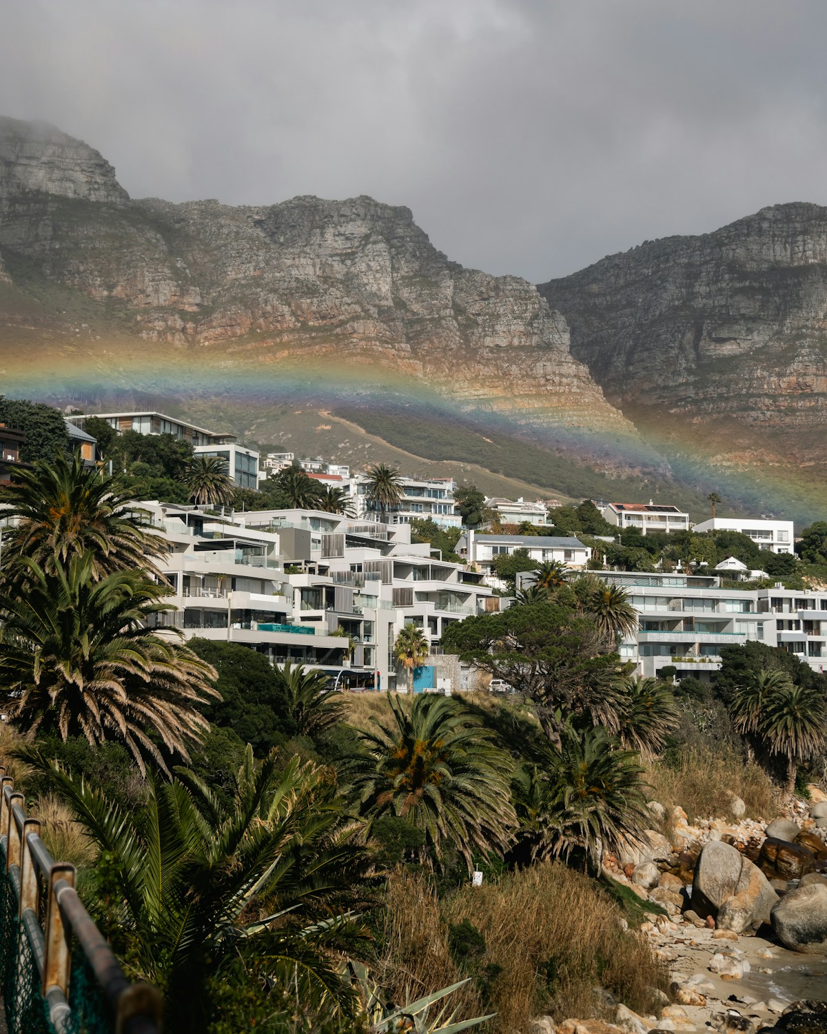 Rainbow arcing over coastal homes and Twelve Apostles mountain at Camps Bay, Cape Town, South Africa