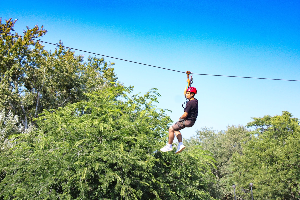 Person riding a zip line through dense forest canopy — Garden Route adventure activities, South Africa