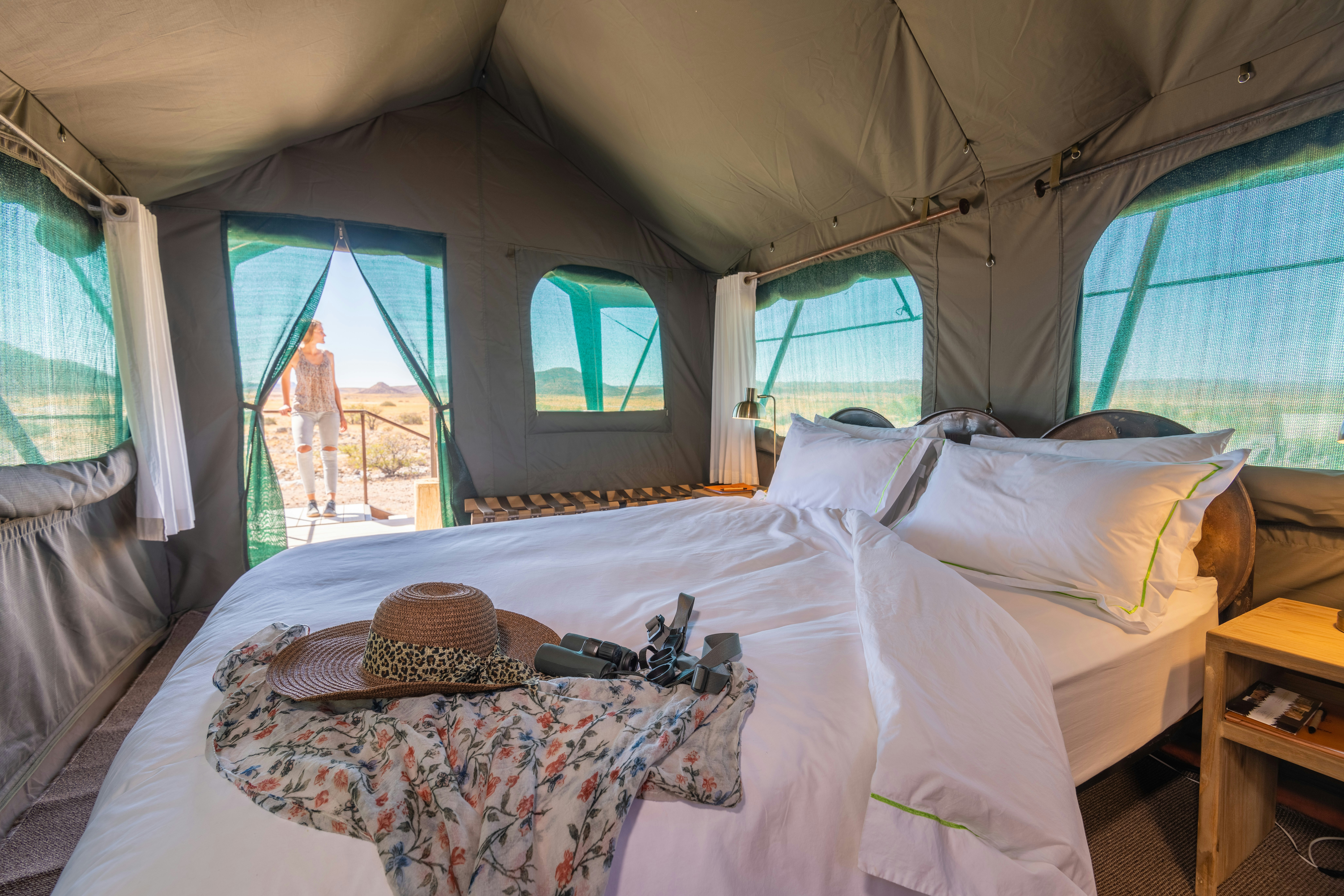 Luxury safari tent interior with white bedding and binoculars — game lodge accommodation near Kruger, South Africa