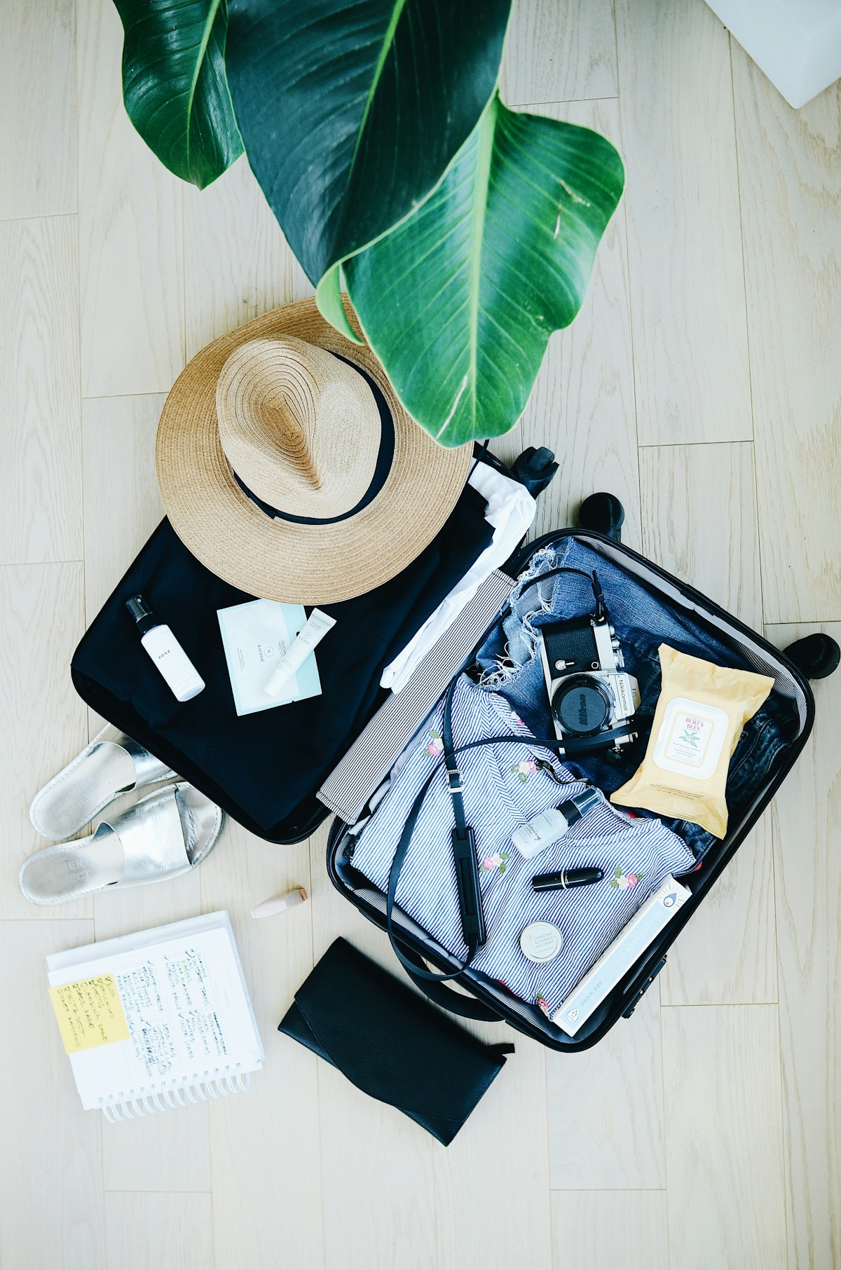 An open suitcase being packed with clothing and travel gear