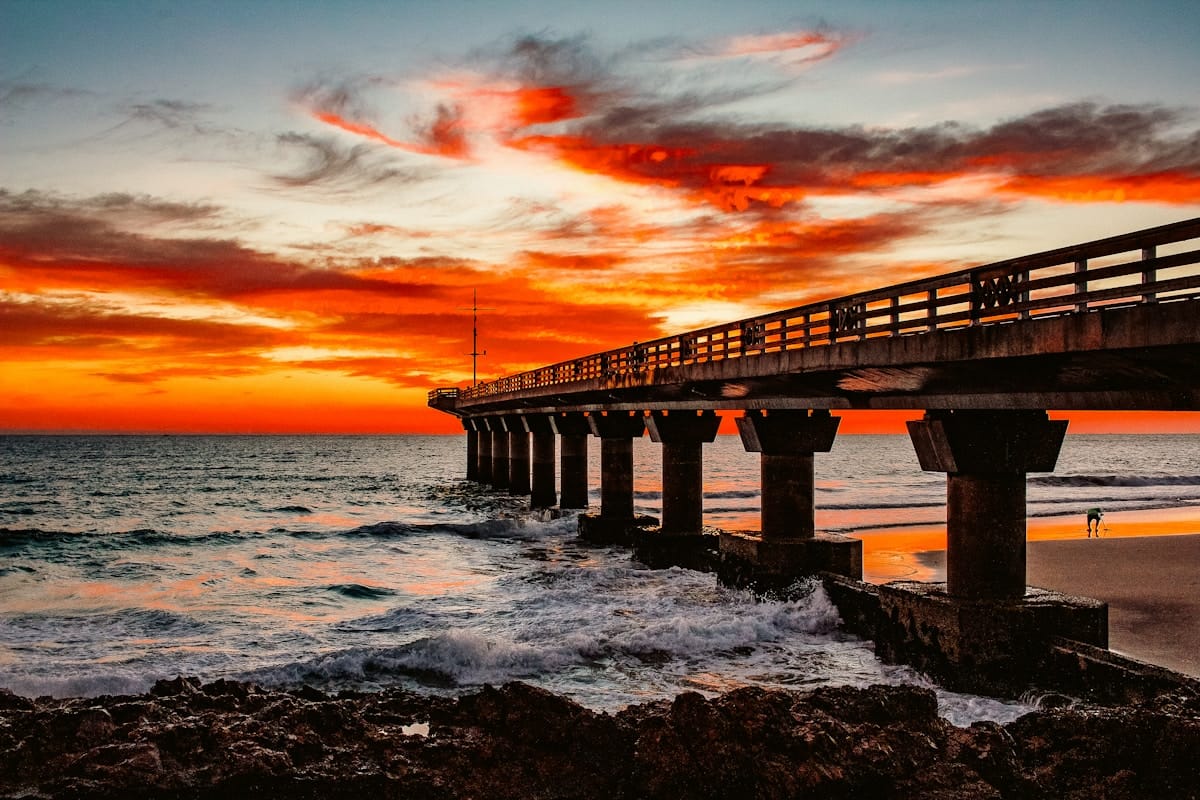 Dramatic fiery sunset over a coastal pier and crashing waves, Eastern Cape, South Africa