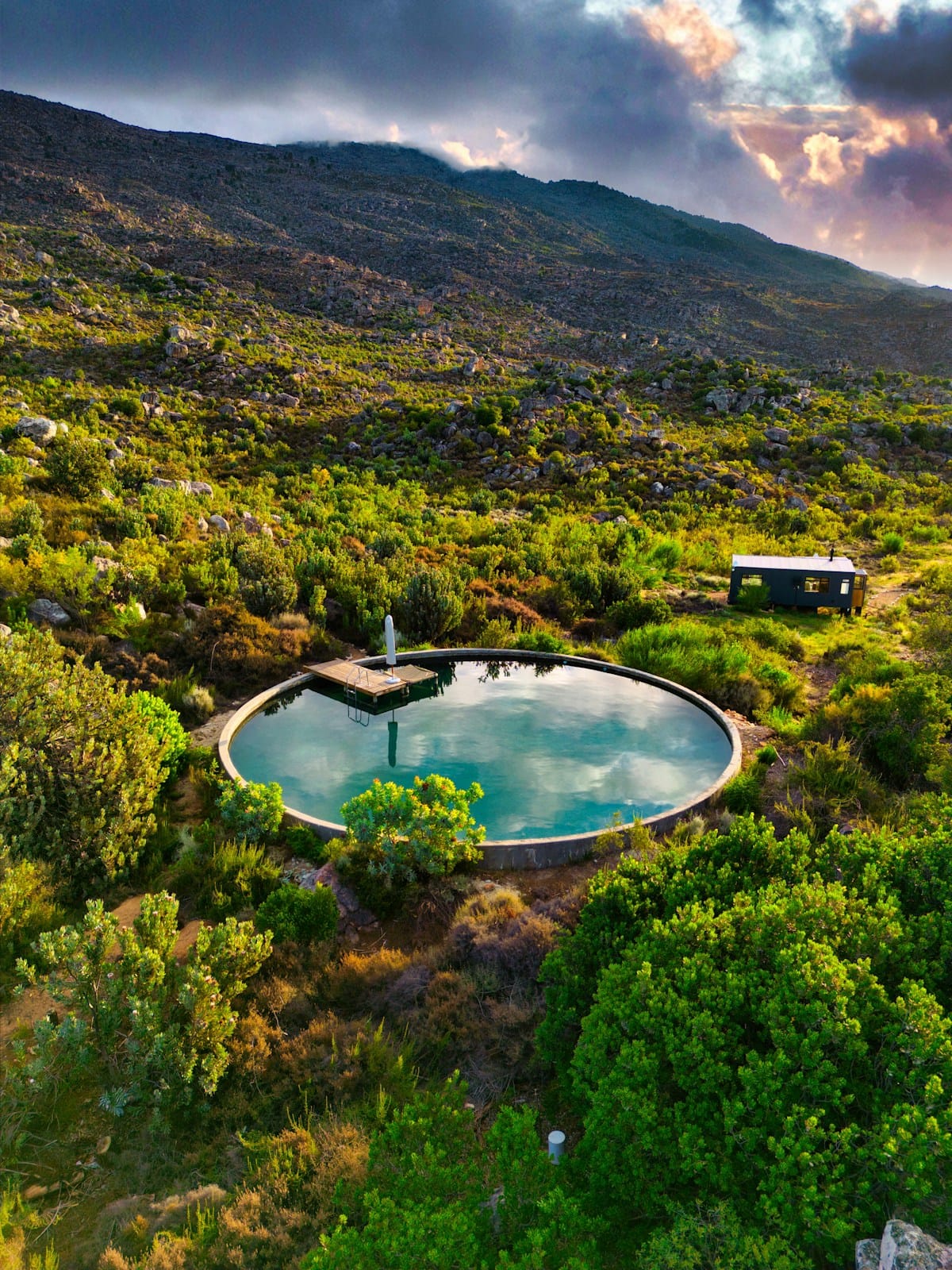 Circular boutique hotel pool surrounded by fynbos and mountains at sunset, South Africa